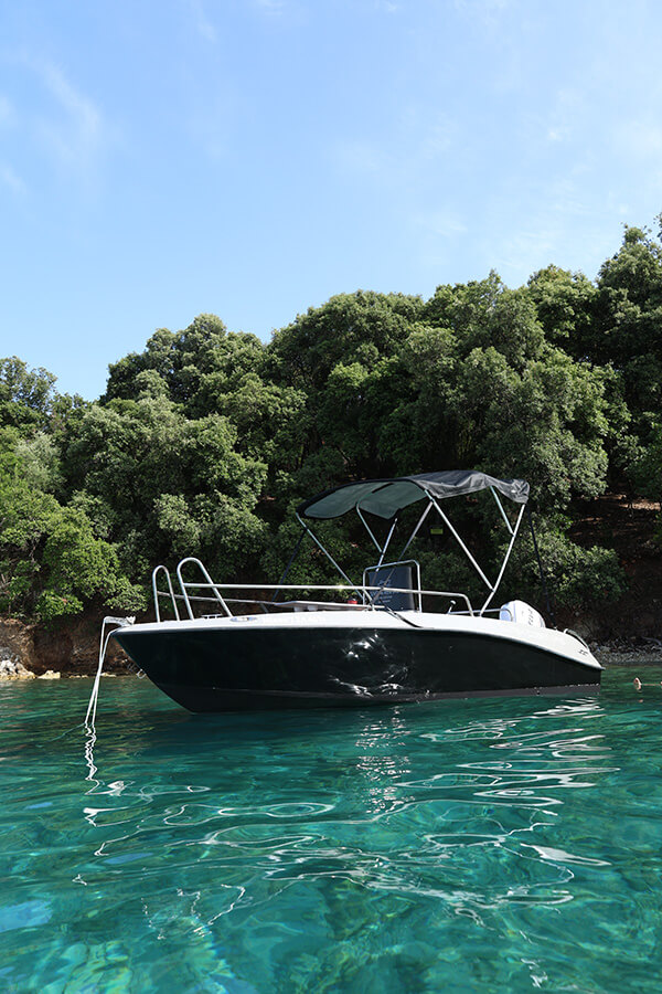 Isatek Cobra, a 40hp no-license rental boat, anchored in a turquoise bay in Sivota, Lefkada.